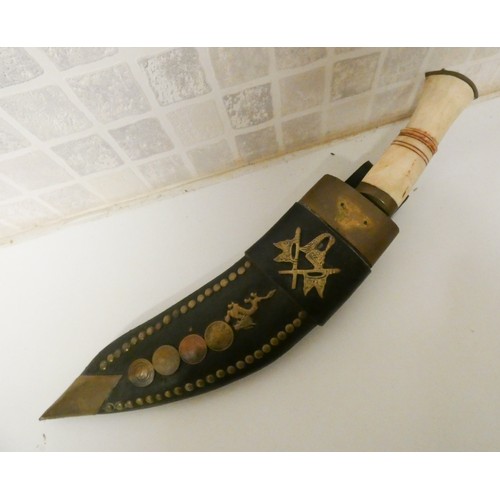 244 - A Kukri in a brass studded and coin decorated leather scabbard