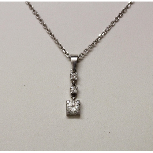 549 - An 18ct white gold modern diamond pendant, set three brilliant cut diamonds of graduated size, on an... 