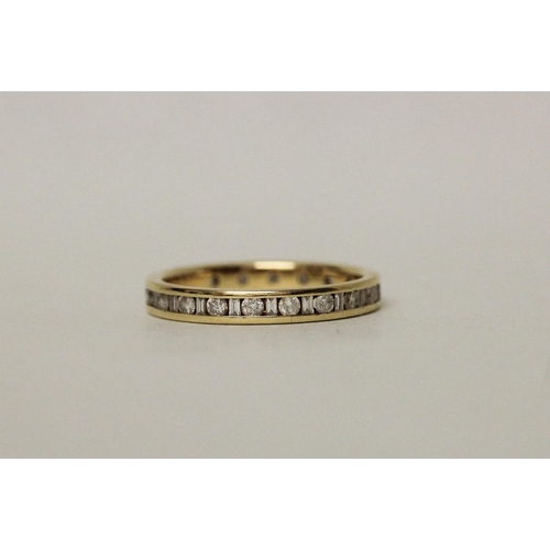 557 - A modern 18ct yellow gold full diamond eternity ring, channel set with alternate baton and brilliant...