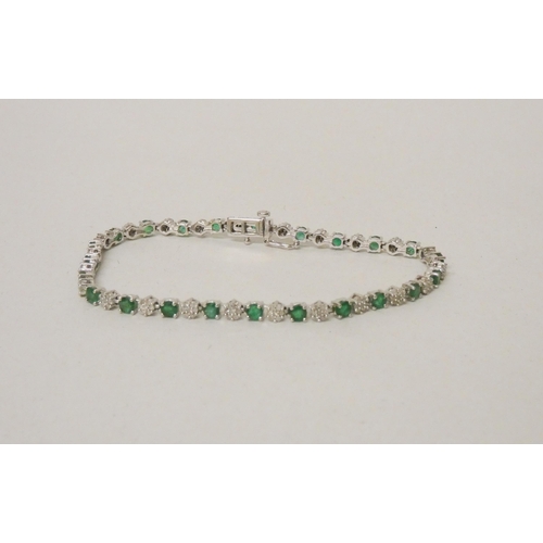 568 - An emerald and diamond line bracelet in 9ct white gold, hallmarked, 19cm long, 8.3 grams