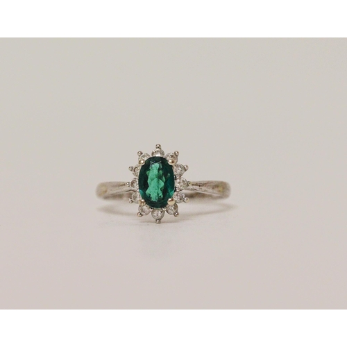 569 - A modern emerald and diamond oval cluster ring on hallmarked 9ct white gold band, ring size M, 2.2 g...