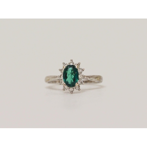 569 - A modern emerald and diamond oval cluster ring on hallmarked 9ct white gold band, ring size M, 2.2 g...