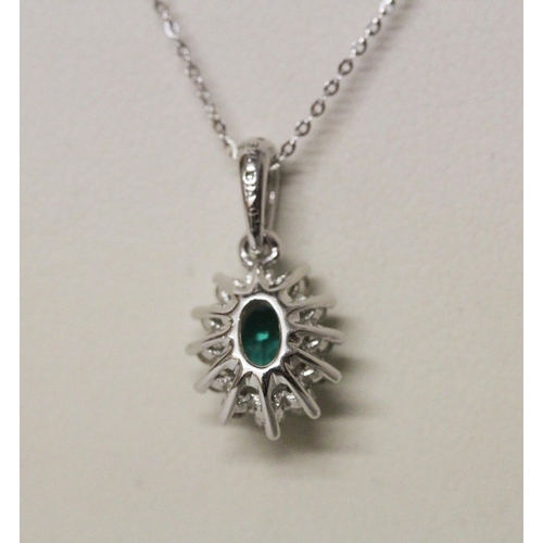 570 - A modern emerald and diamond oval cluster pendant on a fine 9ct white gold chain. 1.9 grams...