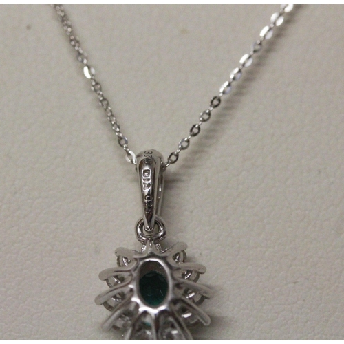 570 - A modern emerald and diamond oval cluster pendant on a fine 9ct white gold chain. 1.9 grams...