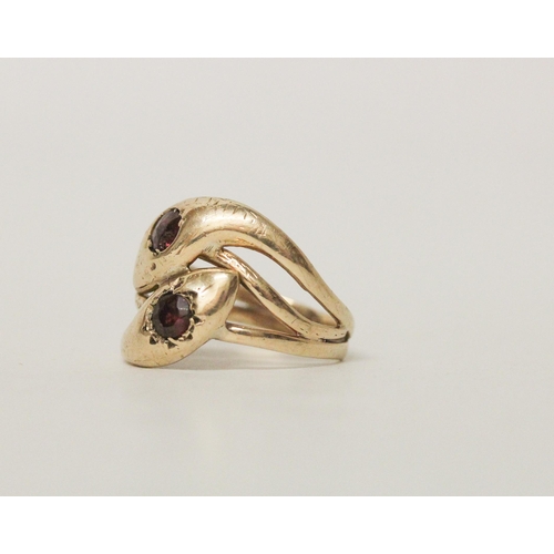 573 - A 9ct yellow gold double snake head ring set with garnets. Hallmarked, ring size S. 4.1 grams