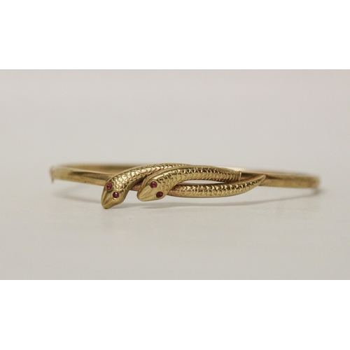 616 - A 9ct yellow gold double snakes head hinged bangle, the snakes with ruby eyes, 4.3 grams