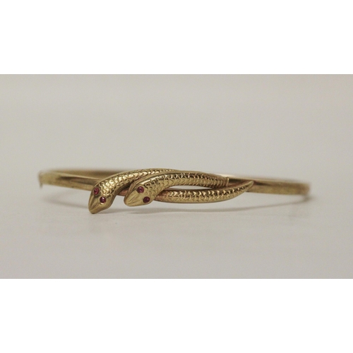 616 - A 9ct yellow gold double snakes head hinged bangle, the snakes with ruby eyes, 4.3 grams