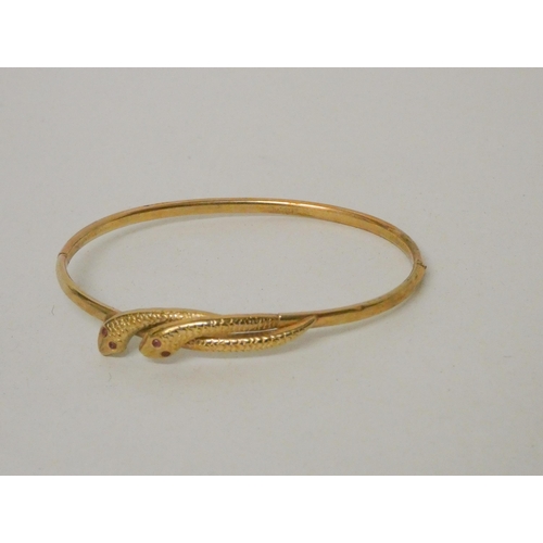 616 - A 9ct yellow gold double snakes head hinged bangle, the snakes with ruby eyes, 4.3 grams