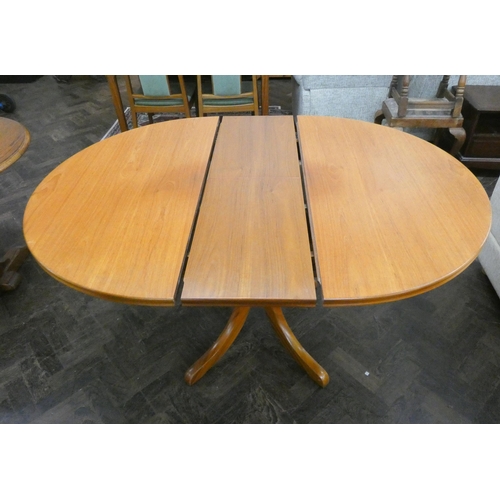 61 - A circular teak extending dining table and four matching slat back chairs with pink upholstered seat... 