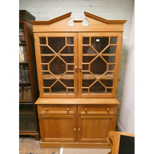 382 - An antique wax reclaimed pine kitchen dresser or bookcase with broken swan neck pediment above astra... 