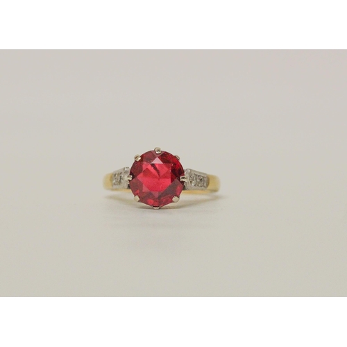 506 - An 18ct yellow gold dress ring, claw set with a large red stone to diamond set shoulders. Hallmarked... 