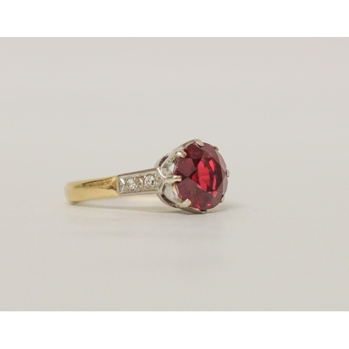 506 - An 18ct yellow gold dress ring, claw set with a large red stone to diamond set shoulders. Hallmarked... 