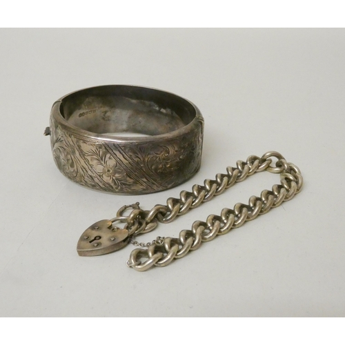 550 - A wide silver bangle with engraved design and a silver curb link chain bracelet with heart shaped pa... 