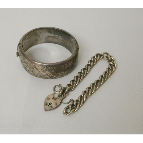 550 - A wide silver bangle with engraved design and a silver curb link chain bracelet with heart shaped pa... 