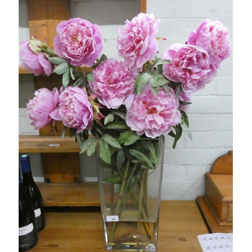 34 - A heavy glass vase containing artificial flowers