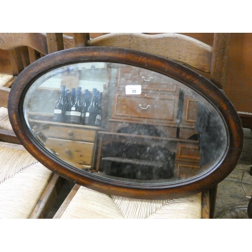 35 - An oval bevelled wall mirror in mahogany frame