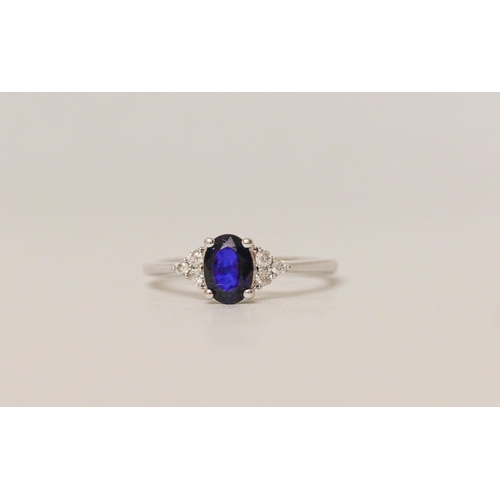 548 - A sapphire and diamond ring, the oval sapphire flanked by brilliant cut diamonds. On 18ct white gold... 