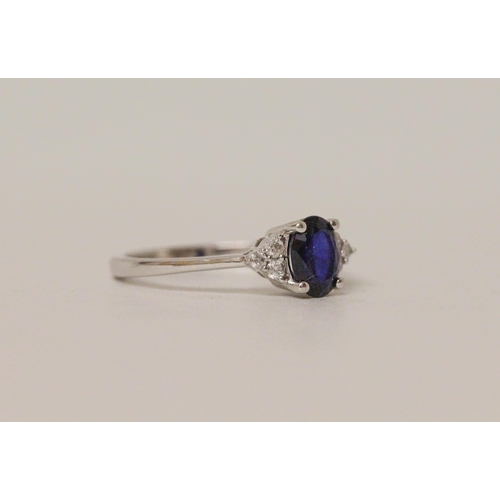 548 - A sapphire and diamond ring, the oval sapphire flanked by brilliant cut diamonds. On 18ct white gold... 