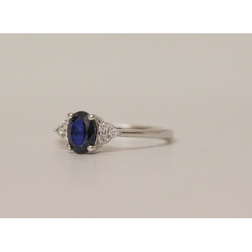 548 - A sapphire and diamond ring, the oval sapphire flanked by brilliant cut diamonds. On 18ct white gold... 