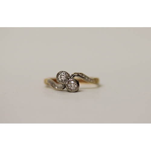 433 - A vintage 18ct & platinum mounted two stone diamond ring, set in a cross over design. Band marked 18... 