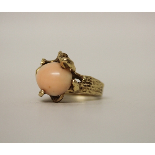 449 - A coral dress ring, the oval angel coral within seaweed inspired naturalistic mount, in unmarked yel... 