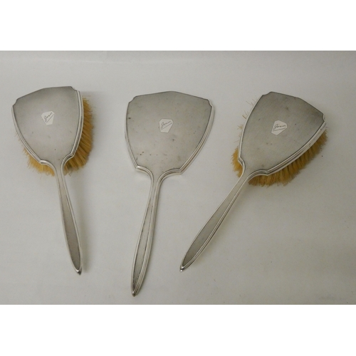 435 - A three piece silver backed hairbrush set, engine turned backs engraved Joan.