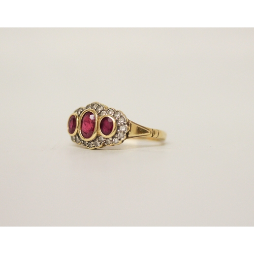 458 - A ruby and diamond three stone cluster ring on an 18ct yellow gold band, ring size M, 4.2 grams