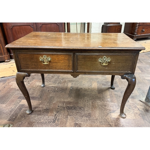 101 - An antique style oak hall table fitted two drawers with brass handles, raised on cabriole legs