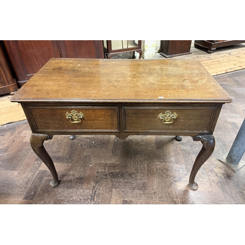 101 - An antique style oak hall table fitted two drawers with brass handles, raised on cabriole legs