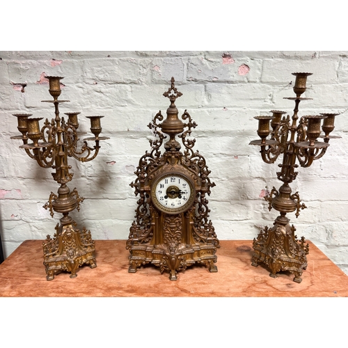 108 - An ornate gilt metal French three piece clock garniture comprising mantel clock with urn finial and ... 