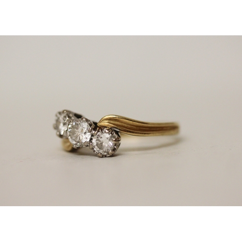 424 - A three stone diamond ring, the three brilliant cut diamonds claw set in a offset cross over twist d... 