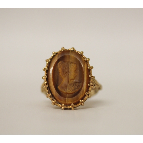 429 - A carved tigers eye cameo dress ring, claw set on 9ct gold band, ring size N. Gross weight 5.8g