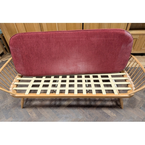 10 - An Ercol blond elm sofa/day bed, model 355, with red cushions...