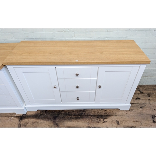 17 - A long low modern white sideboard fitted three centre drawers and cupboards with light oak top and c...
