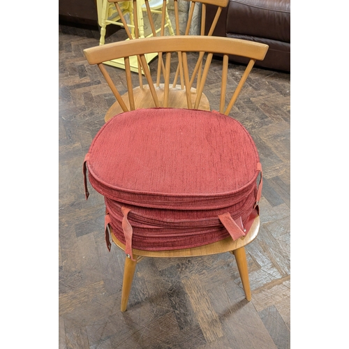 8 - A set of four Ercol blond elm Candlestick 376 spindle back dining chairs, with red seat pads...