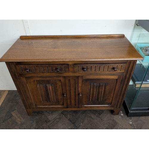18 - A reproduction oak sideboard fitted two drawers and linen fold panel doors, 4' wide