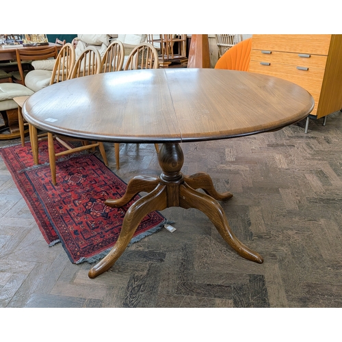 2 - An Ercol Chester oval extending dining table with centre leaf standing on turned pillar and quadrupl... 