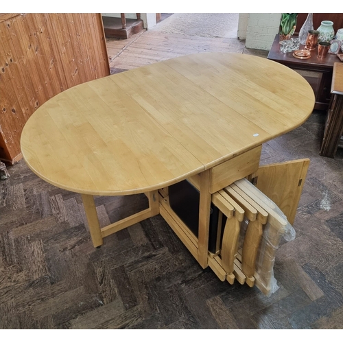 54 - A light beech finished butterfly oval dop leaf table and four stack away chairs with brown vinyl sea... 