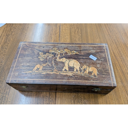 105 - A teak inlaid glove box, the lid decorated with elephants -  containing bosuns whistles and costume ... 