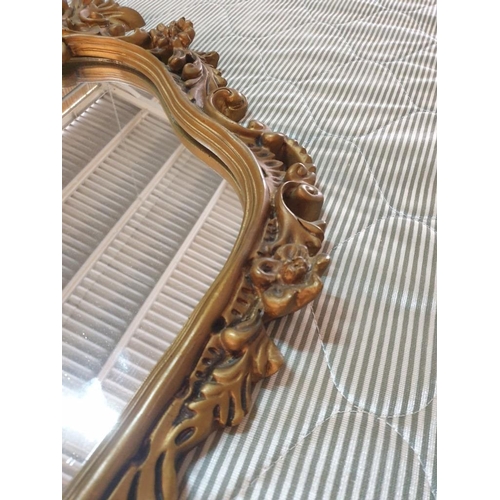 129 - Shapely Wall Mirror with Elaborate Gold Colour Frame (90cm x 64cm) (Believed to be metallic or heavy... 