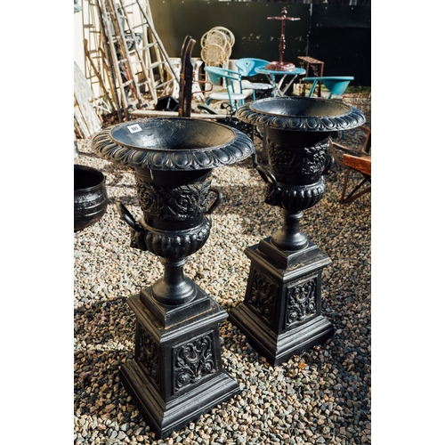 665 - Pair of decorative cast iron urns on pedestals.