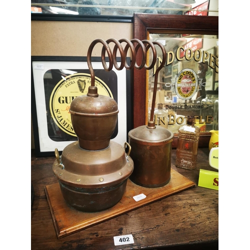 1010 - Miniture copper whiskey still mounted on a mahogany base {47 cm H x 46 cm W}.