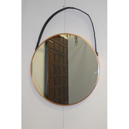 180 - Copper framed mirror with hanging leather strap {76 cm Dia. X 5 cm D}.