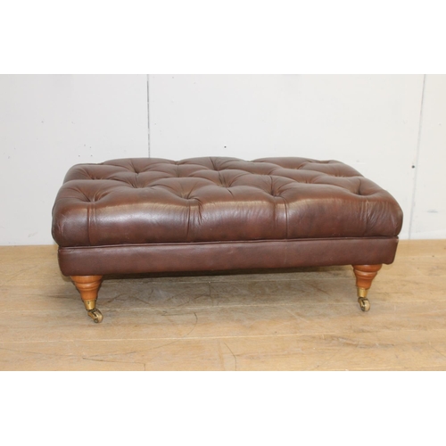 372 - Deep buttoned leather upholstered footstool raised on turned legs and brass castors {35 cm H x 94 cm... 