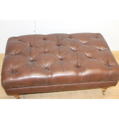 372 - Deep buttoned leather upholstered footstool raised on turned legs and brass castors {35 cm H x 94 cm... 