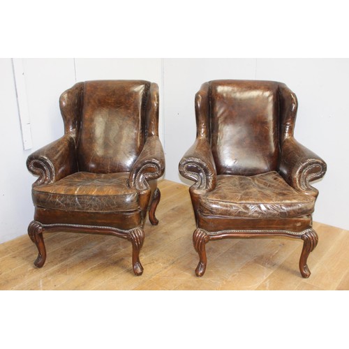 240 - Pair of brown leather upholstered wing back armchairs raised on cabriole legs in the Queen Anne styl... 