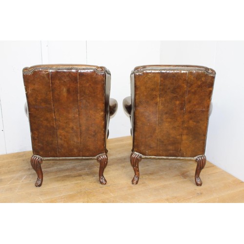 240 - Pair of brown leather upholstered wing back armchairs raised on cabriole legs in the Queen Anne styl... 