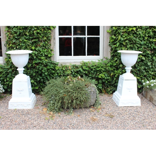 61 - Pair of cast iron urns mounted the bases decorated with urns and garlands { 98cm H X 45cm Dia }.