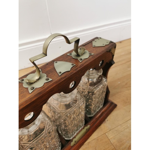 1038 - Edwardian oak tantalus with silverplated mounts three cut glass bottles  and original key { 33cm H X... 