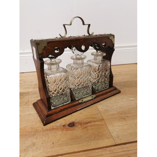 1038 - Edwardian oak tantalus with silverplated mounts three cut glass bottles  and original key { 33cm H X... 